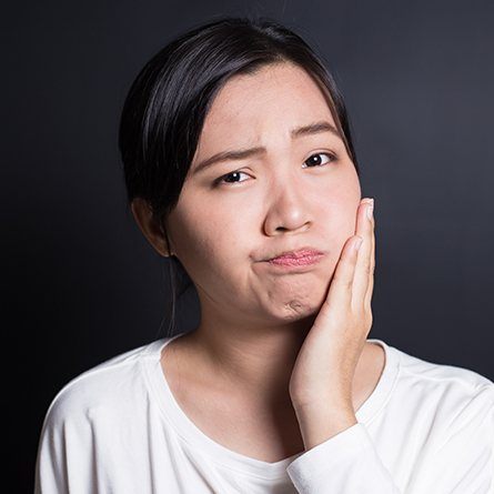 woman holding cheek in pain