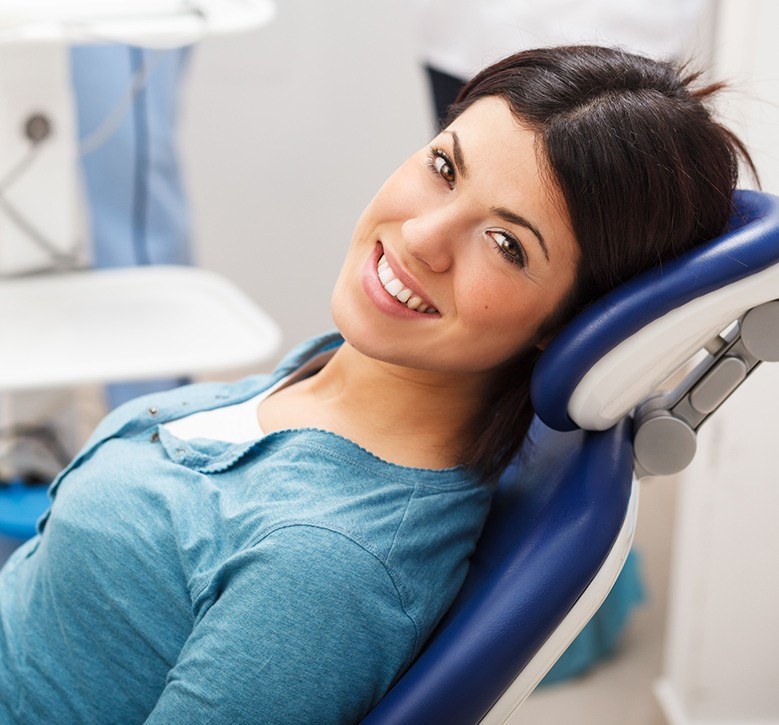 woman laying back in exam chair smiling up