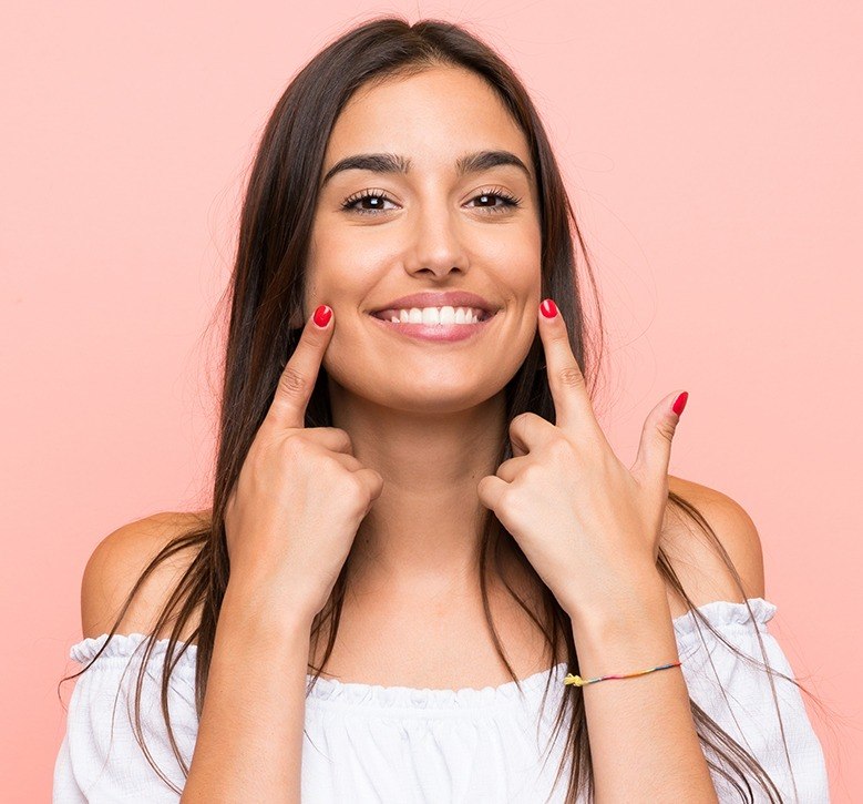 woman pointing with both fingers to smile