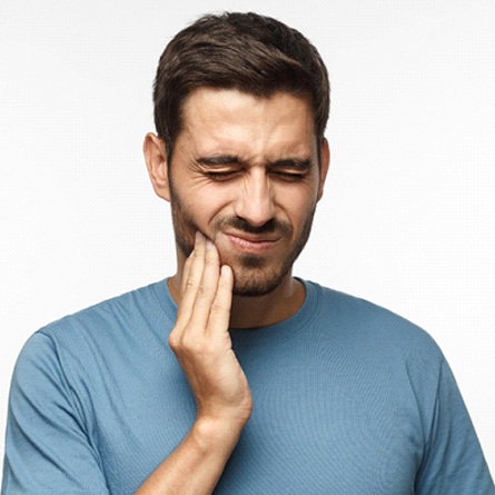 Hombre con la mano en la mejilla experimentando dolor de mandíbula