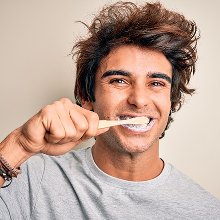 Man in grey shirt brushing his teeth