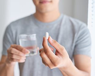 man holding pill and water