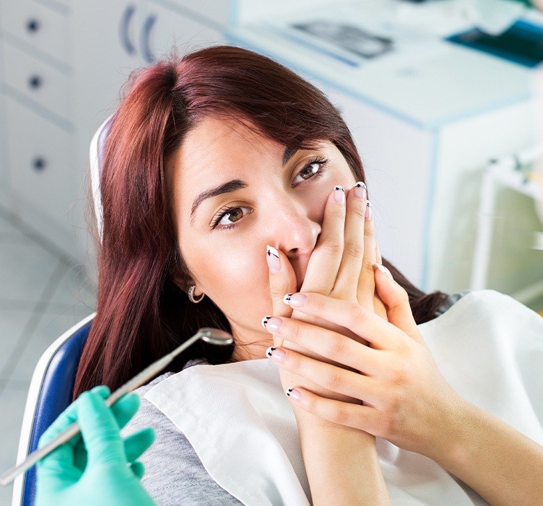 woman covering mouth in exam chair