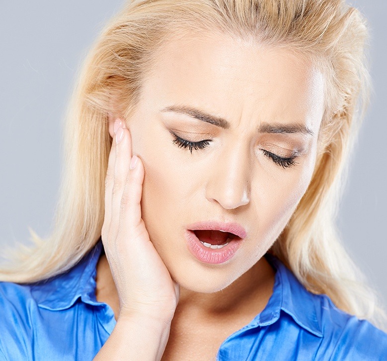 woman holding jaw in pain