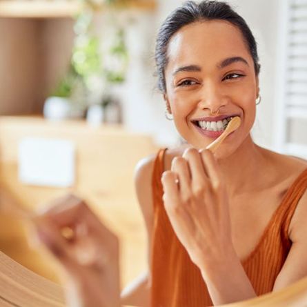 Woman brushing her teeth in front of bathroom mirror