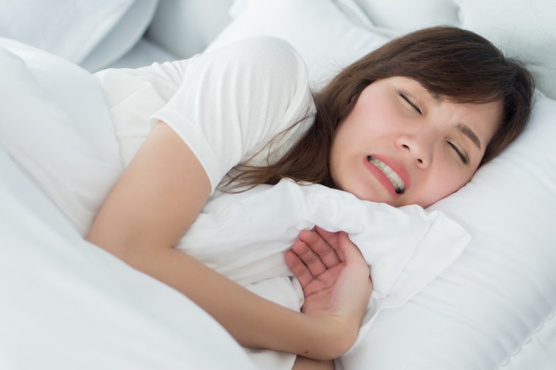 a woman lying in bed clenching her teeth