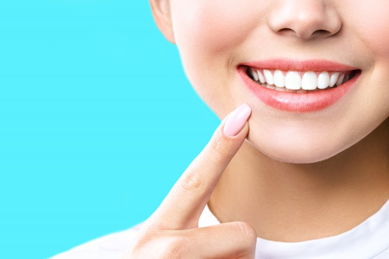 an up-close image of a woman pointing to her smile