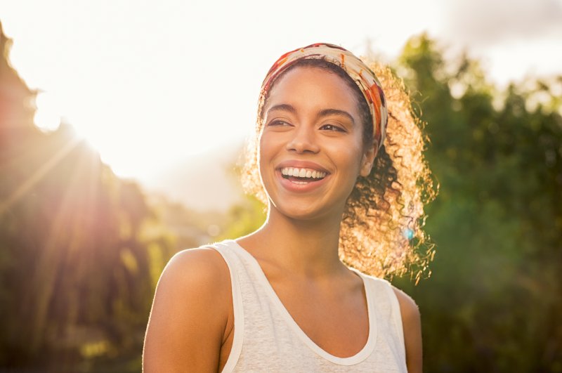 a young woman stands outside smiling because she’s happy