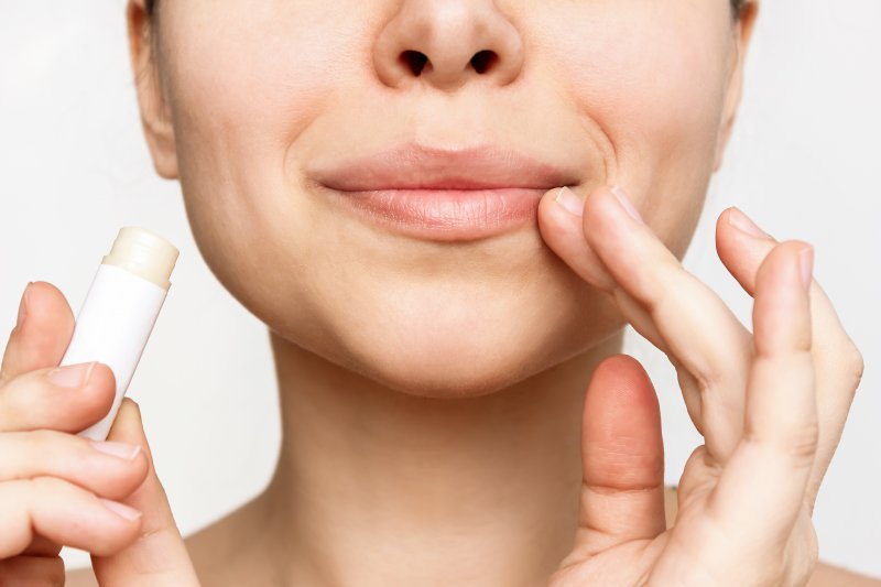 closeup of woman putting on lip balm 