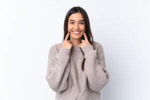 Smiling woman pointing at her bright, beautiful teeth 